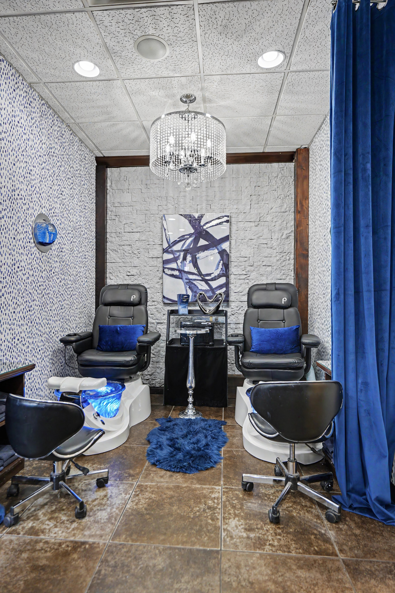 Ovations’ two-chair pedicure room framed by blue curtains and a crystal chandelier
