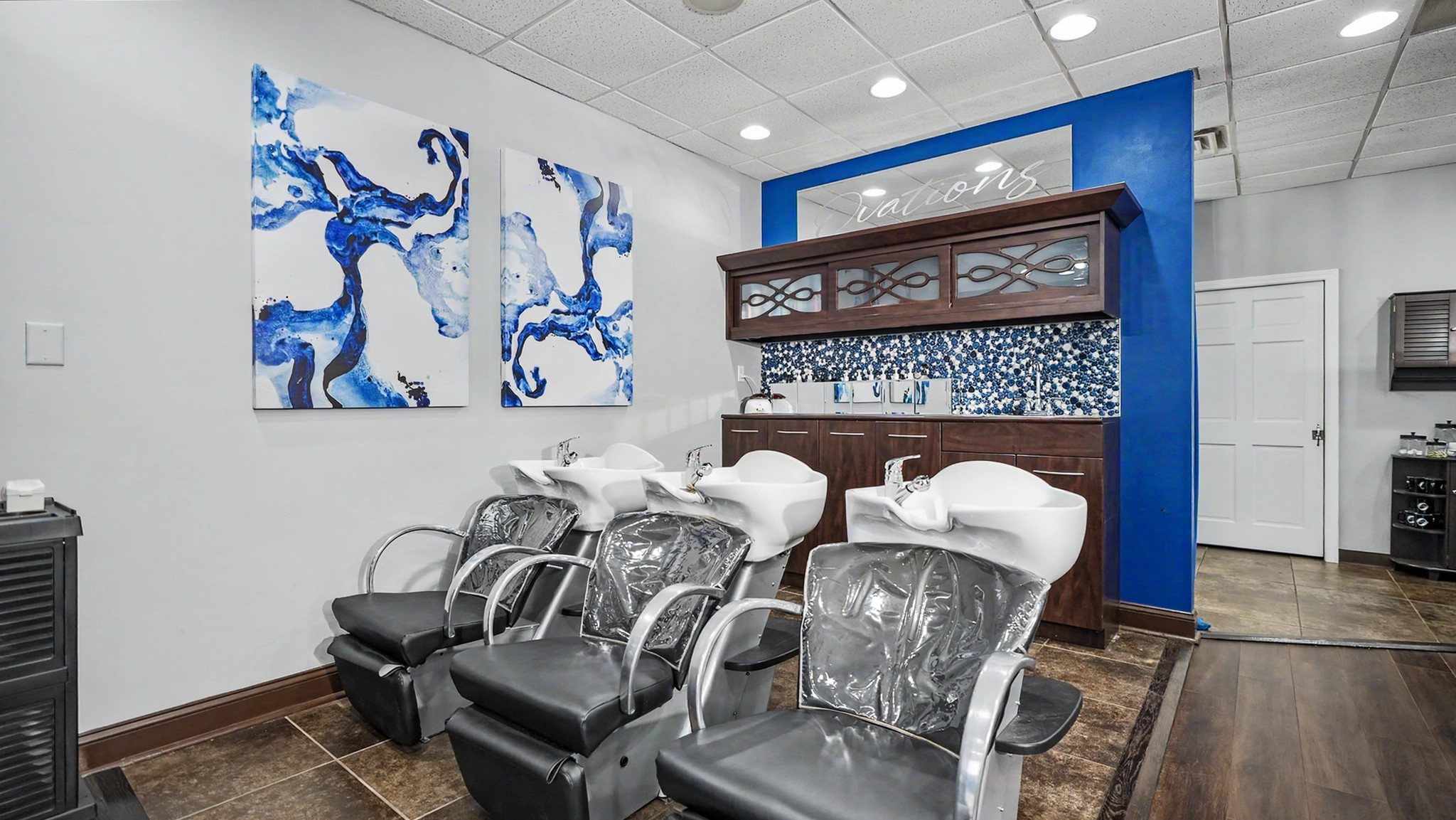 Three wash stations beneath blue artwork and the Ovations salon sign